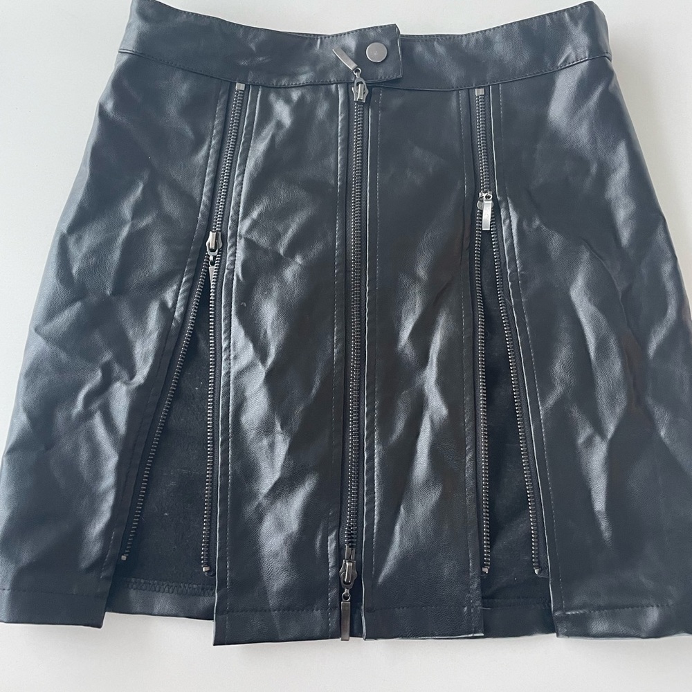 Black leather skirt with two front zippers that makes splits up the skirt.